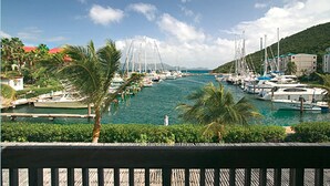 A marina with boats docked, palm trees, and a view of a hilly landscape. - Sapphire Beach Resort (St. Thomas)