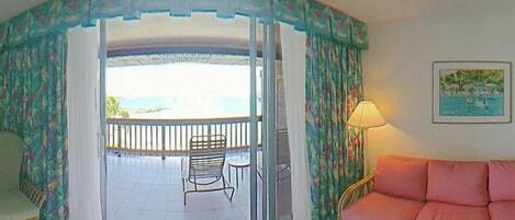 A room with a balcony, a sofa, and a table.