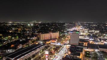 A cityscape at night with illuminated buildings, roads, and a prominent hotel with a modern design.