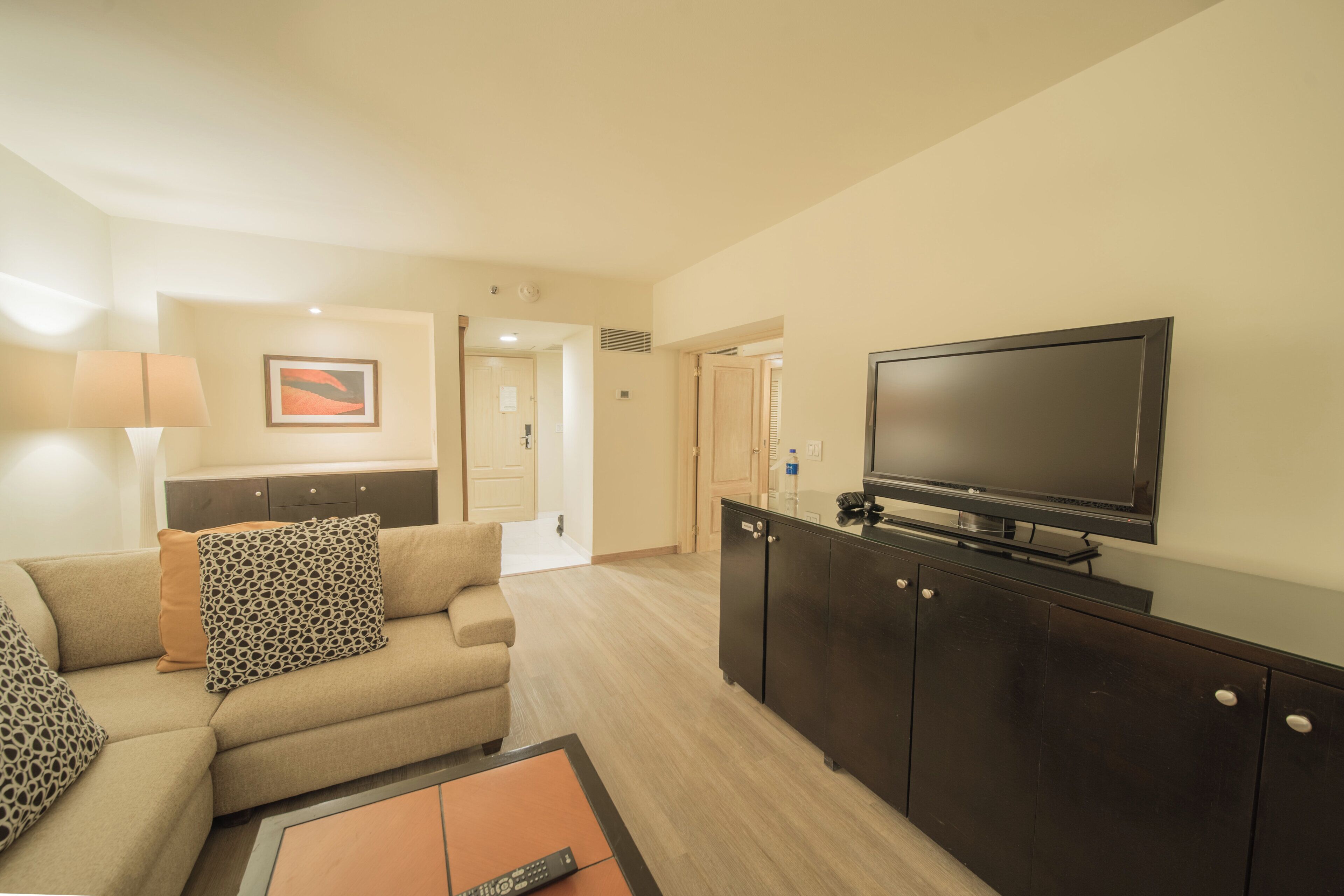 A hotel room with a sofa, a coffee table, a television, and a cabinet.