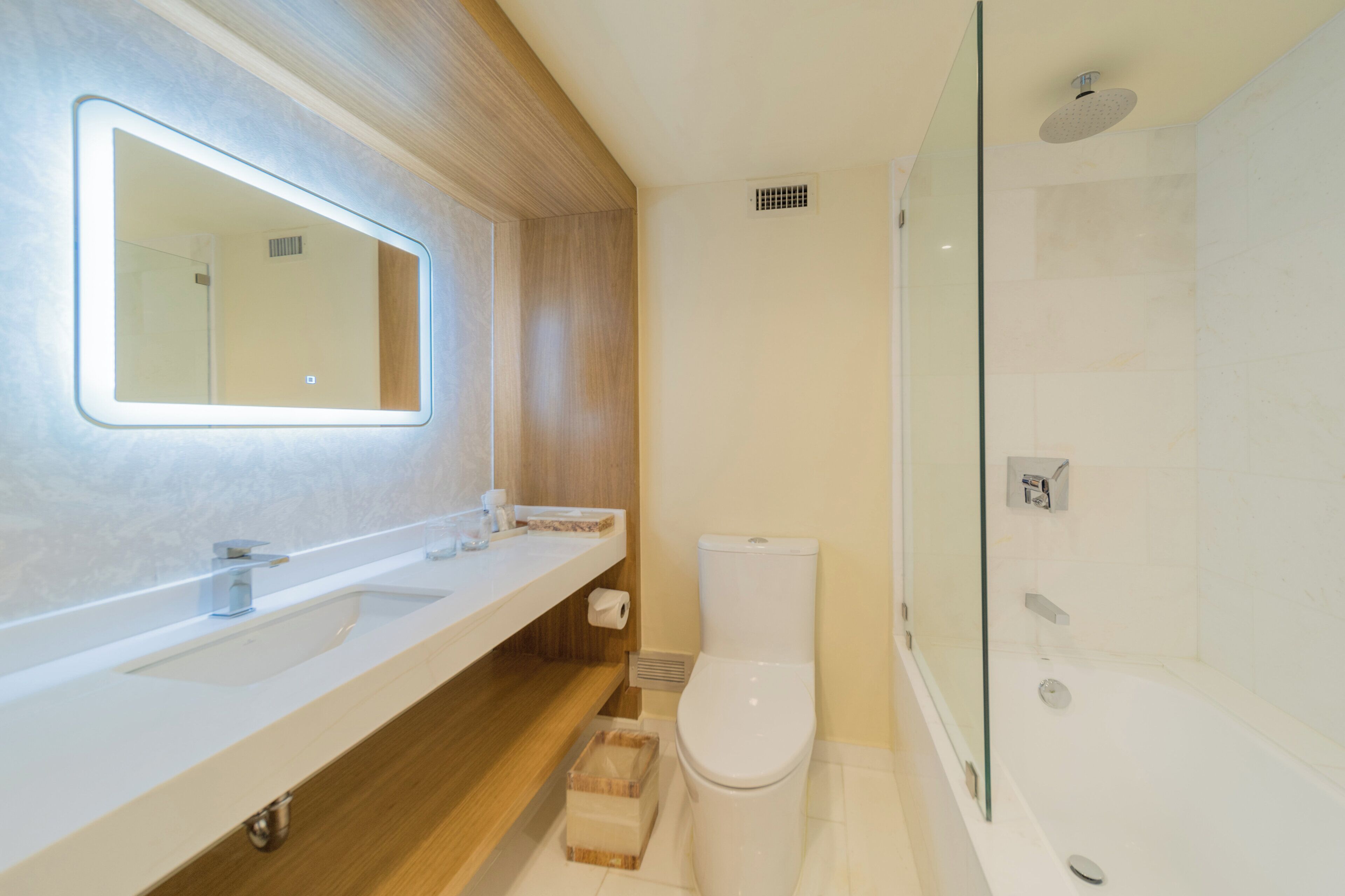 A modern bathroom with a large mirror, a toilet, and a shower area.