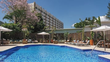 Una piscina al aire libre, sombrillas, sillones reclinables de piscina