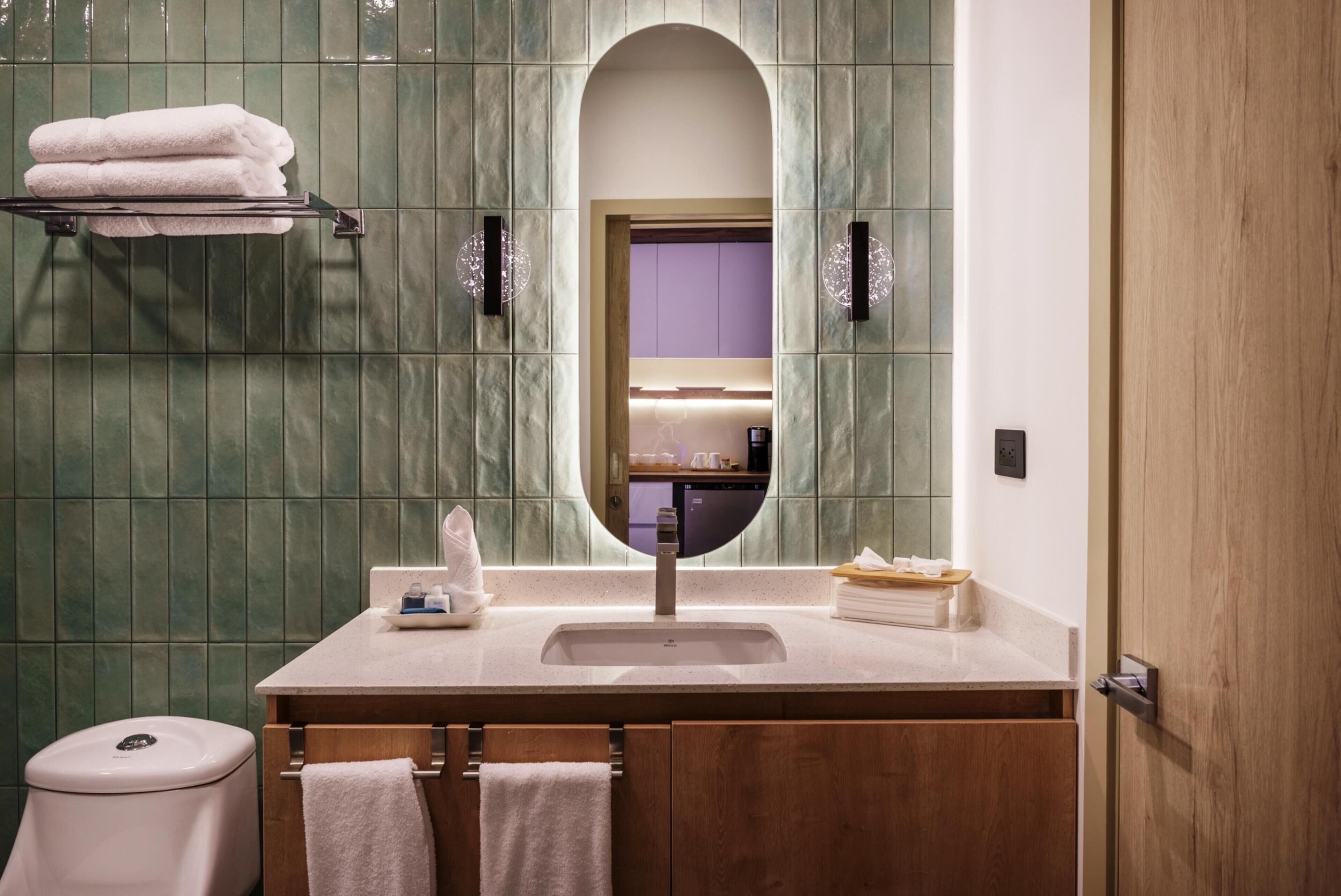 Un baño con tocador, inodoro, espejo y perchero para toallas.