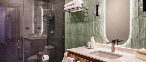 A modern bathroom with a glass shower enclosure, a toilet, and a sink with a mirror.