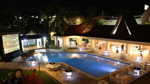 A pool area with lounge chairs and tables, a stage with musical equipment, and a building with a sloped roof. - Best Western Plus Hotel Terraza (San Salvador)