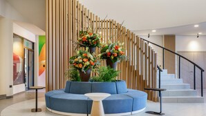 A modern lobby with a blue sofa, a round table, and a staircase with wooden railings. - Best Western Plus Hotel Terraza (San Salvador)