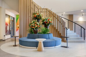 Eine moderne Lobby mit einem blauen Sofa, einem runden Tisch und einer Treppe mit Holzwertungen.