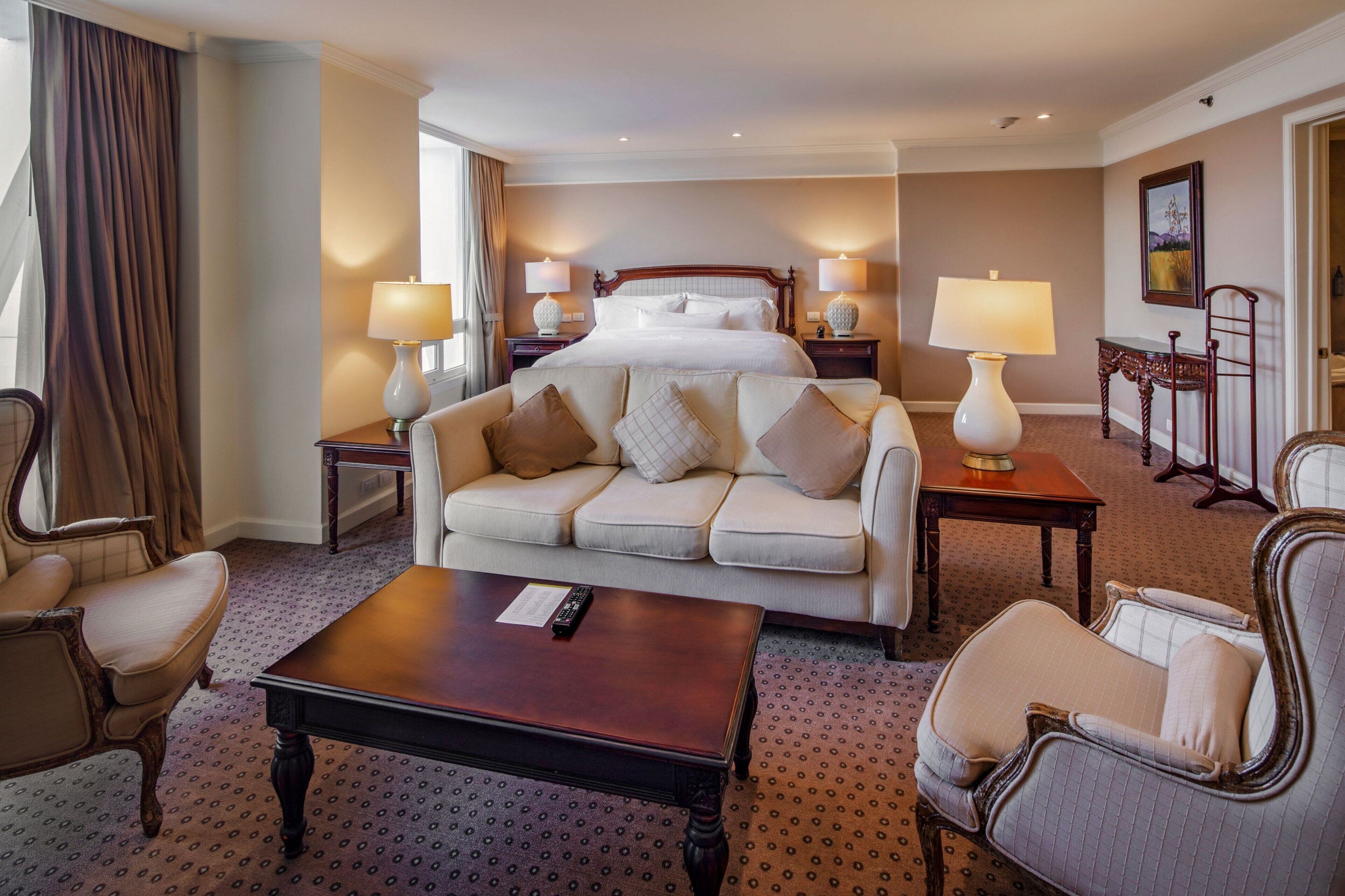 Una habitación de hotel con una cama grande, un sofá, una mesa de centro y dos lámparas.