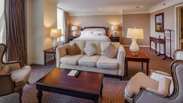 Una habitación de hotel con una cama grande, un sofá, una mesa de centro y dos lámparas.