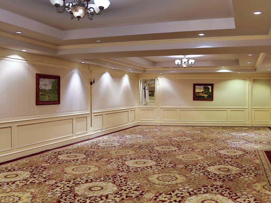 A spacious hallway with a patterned carpet, cream-colored walls, and recessed lighting.