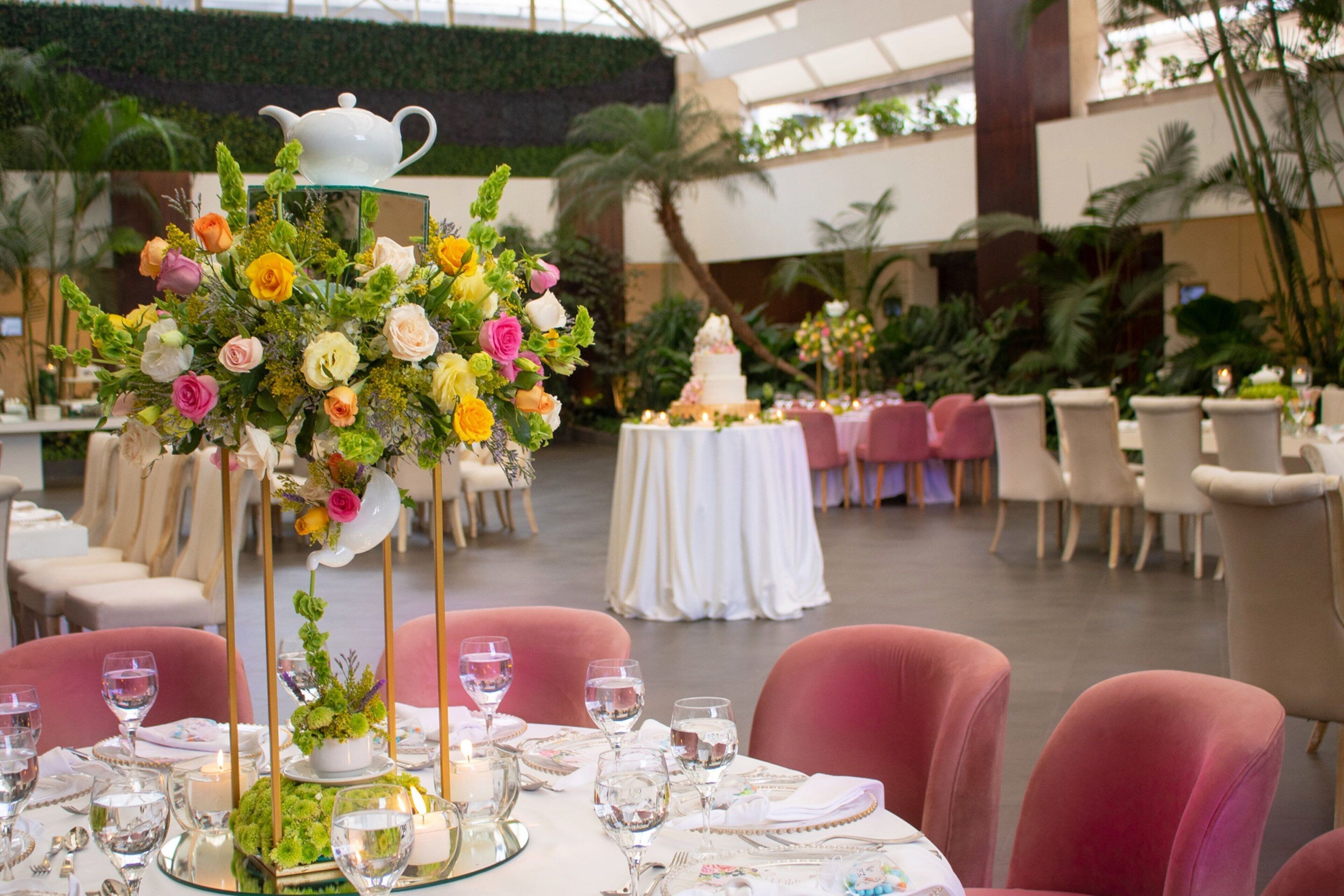 Ein Banketthaus mit runden Tischen, gedeckt für ein Essen, mit floralen Tischdekorationen und einer eleganten Tafelaufsatz.