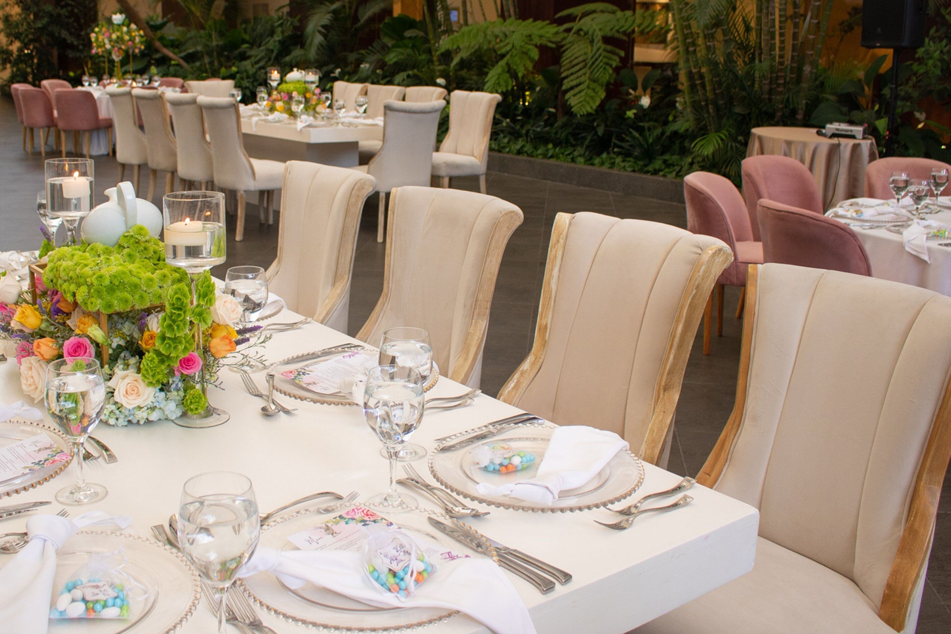 Un espace dédié aux repas, avec des tables dressées pour un événement formel, agrémenté de nappes blanches, de chaises élégantes et de compositions florales.