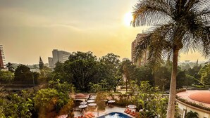 A rooftop pool area with sun loungers and umbrellas, surrounded by palm trees and greenery. - The Westin Camino Real, Guatemala (Guatemala City)