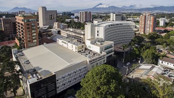 Un hotel moderno con un patio central, rodeado de edificios altos y un paisaje montañoso.