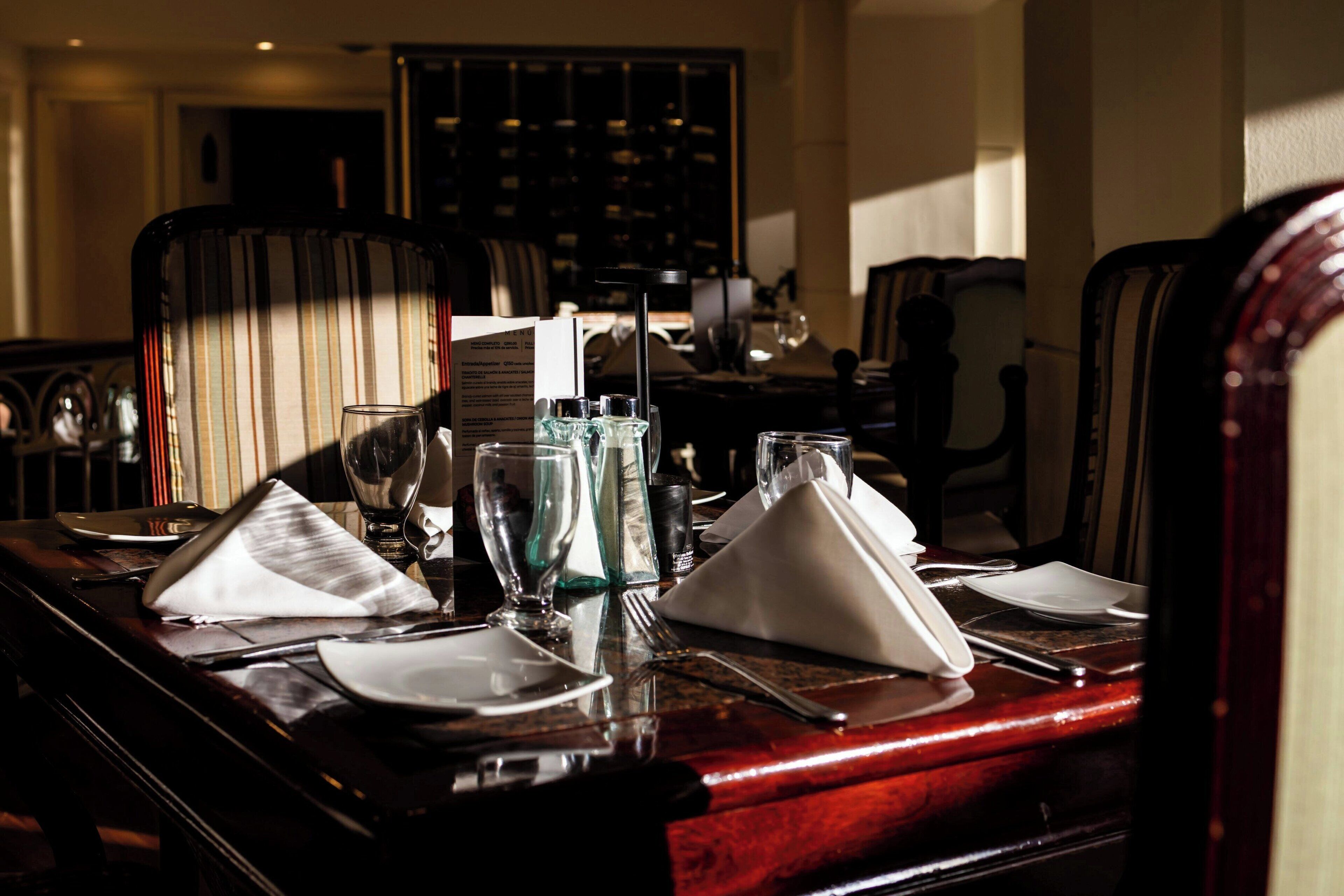 A dining table set with plates, glasses, and cutlery, with a wine glass and a bottle visible.