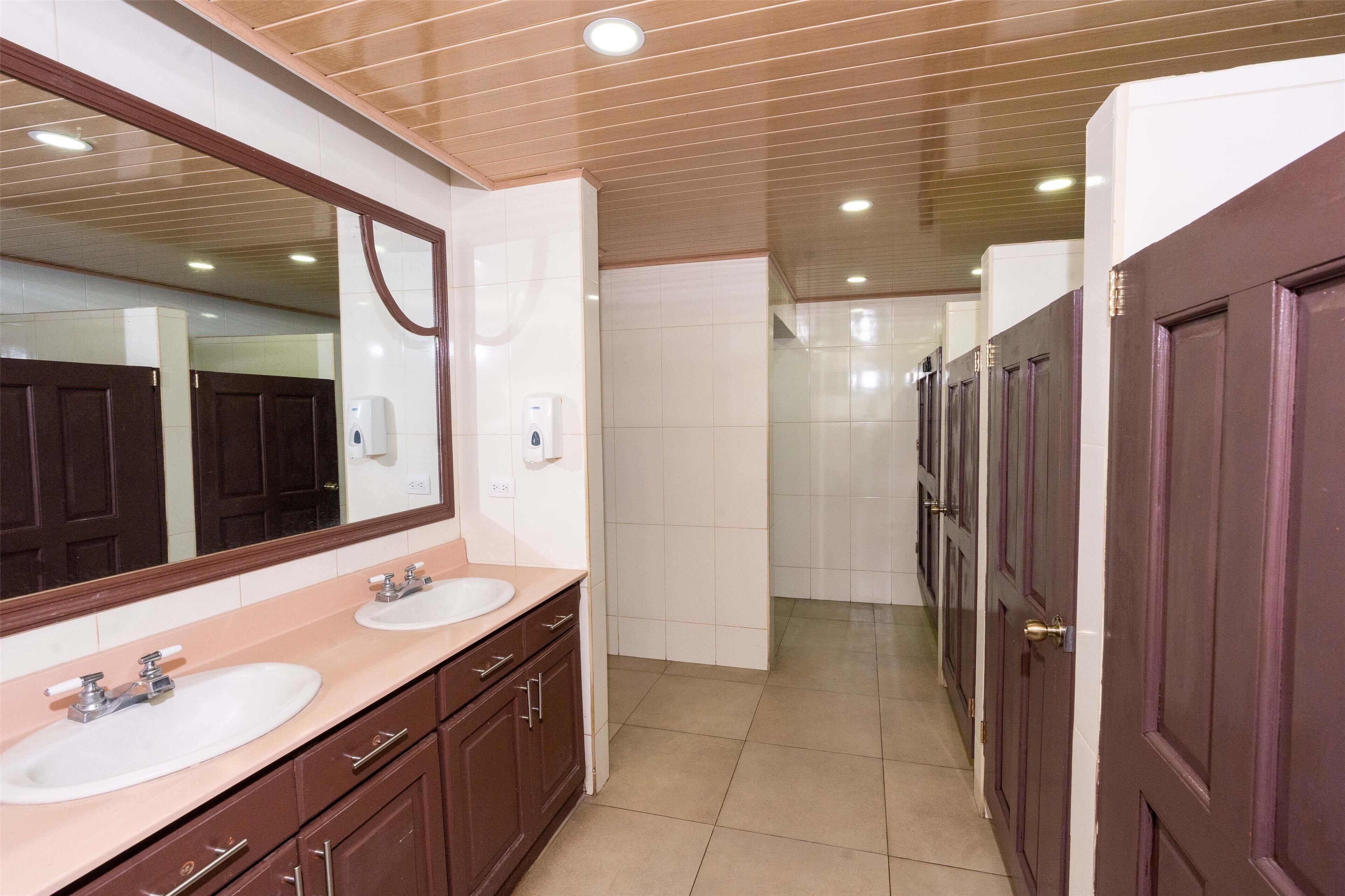 A modern bathroom with two sinks, a large mirror, and wooden panel ceiling.