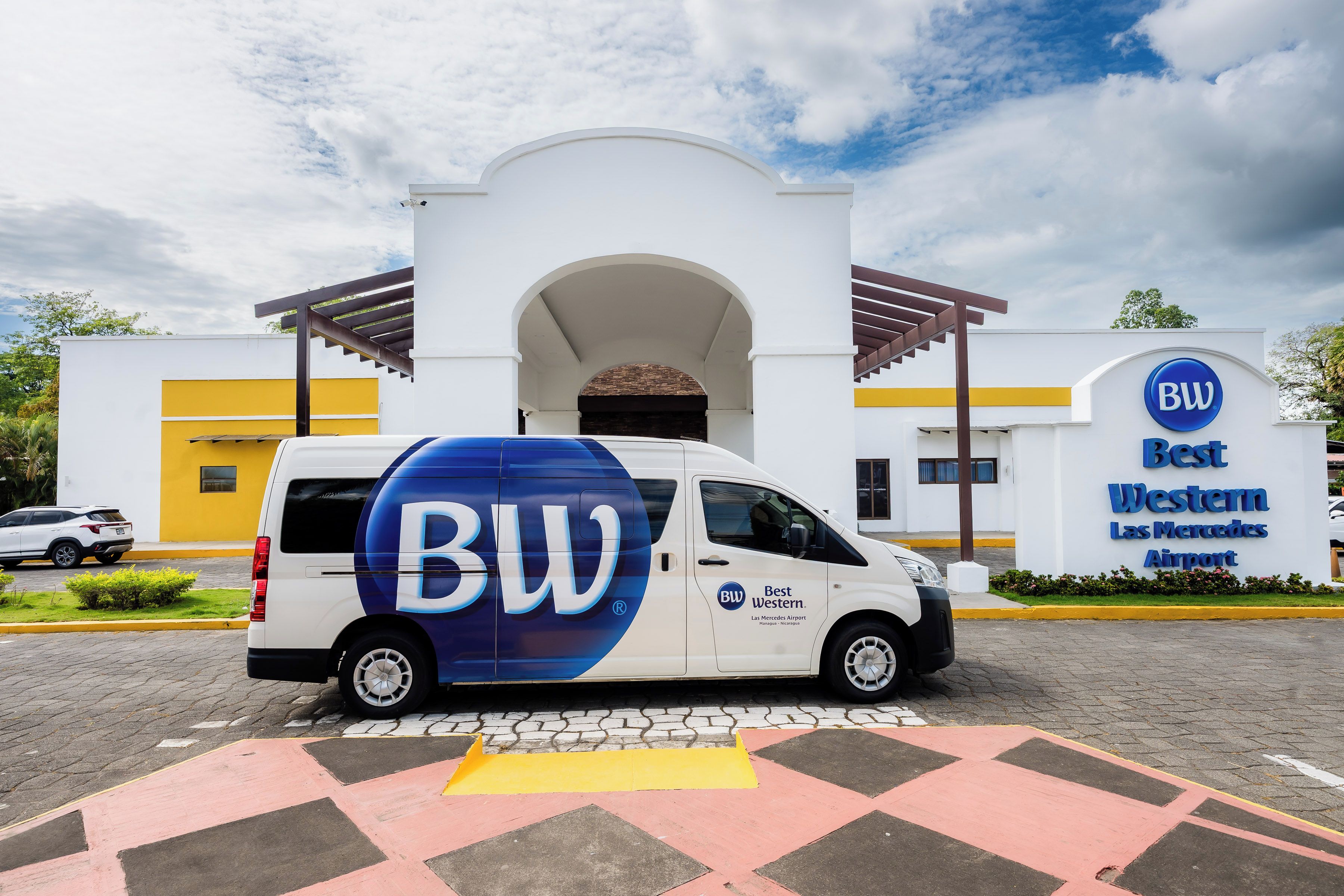 A white van with 'BW' and 'Best Western' branding parked in front of a Best Western hotel.