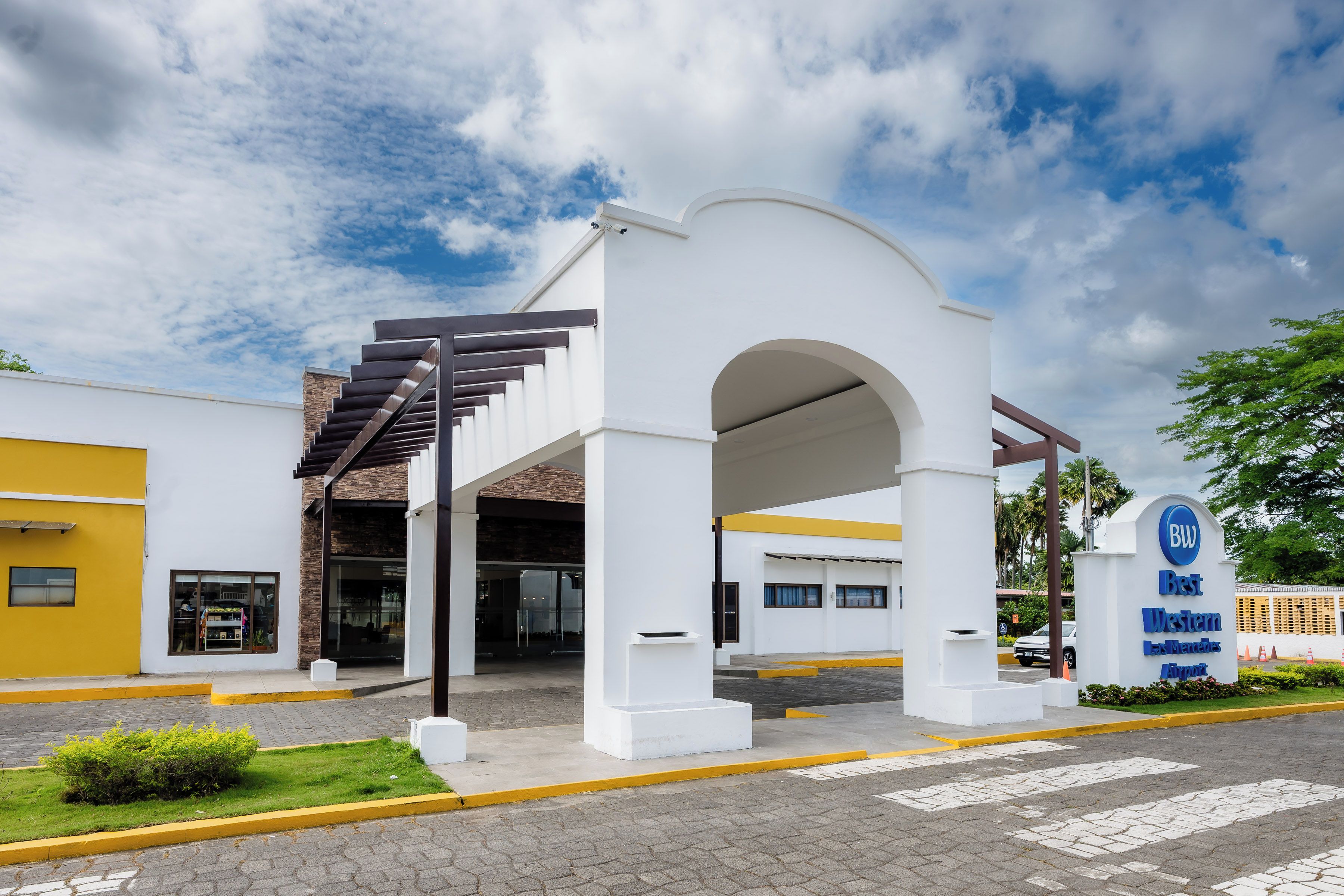 A modern building with a white facade, a covered entrance, and a sign indicating it is a Best Western hotel.