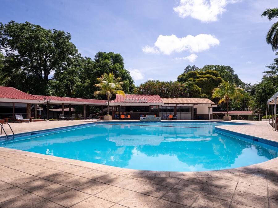 A swimming pool with tiled deck, lounge chairs, and covered seating areas.