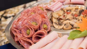 Un piatto assortito di salumi e carni, con prosciutto a fette, salame e funghi.