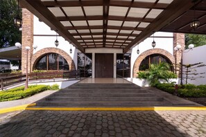 A covered entrance with stone arches, a central door, and steps leading up to a paved area. - Best Western Las Mercedes Airport (Managua)