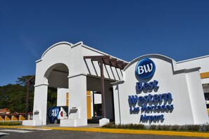 Ingang van Best Western Las Mercedes Airport, met een helderblauwe lucht.