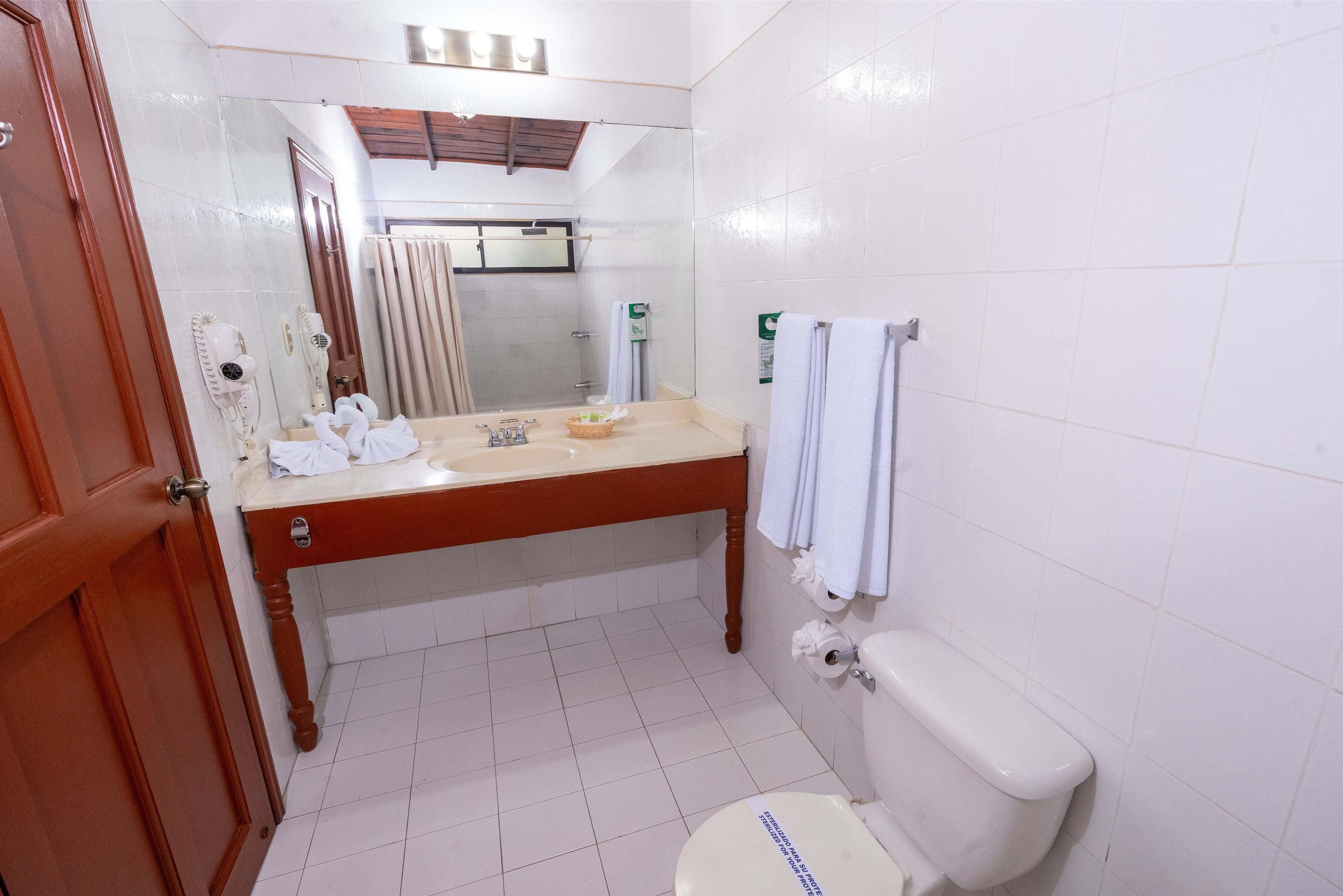 Un bagno con un mobile lavabo in legno, un water, un lavandino e uno specchio.