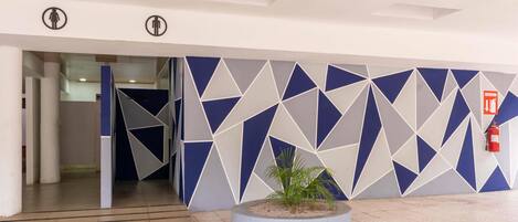 Un intérieur moderne avec des motifs géométriques sur les murs, une plante au centre et un extincteur.