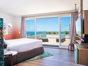 A hotel room with a bed, a desk, a TV, and a balcony with a view of the sea. - Mercure Rio Boutique Hotel Copacabana (Rio de Janeiro)