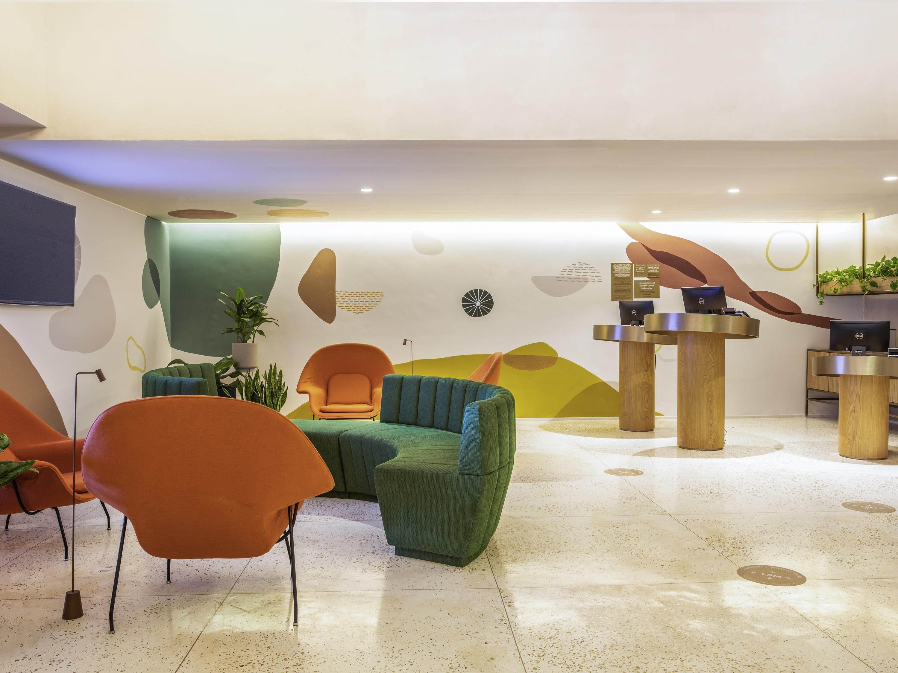 Um hall moderno com balcão de recepção, área de estar e arte decorativa na parede.