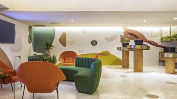 Um hall moderno com balcão de recepção, área de estar e arte decorativa na parede.
