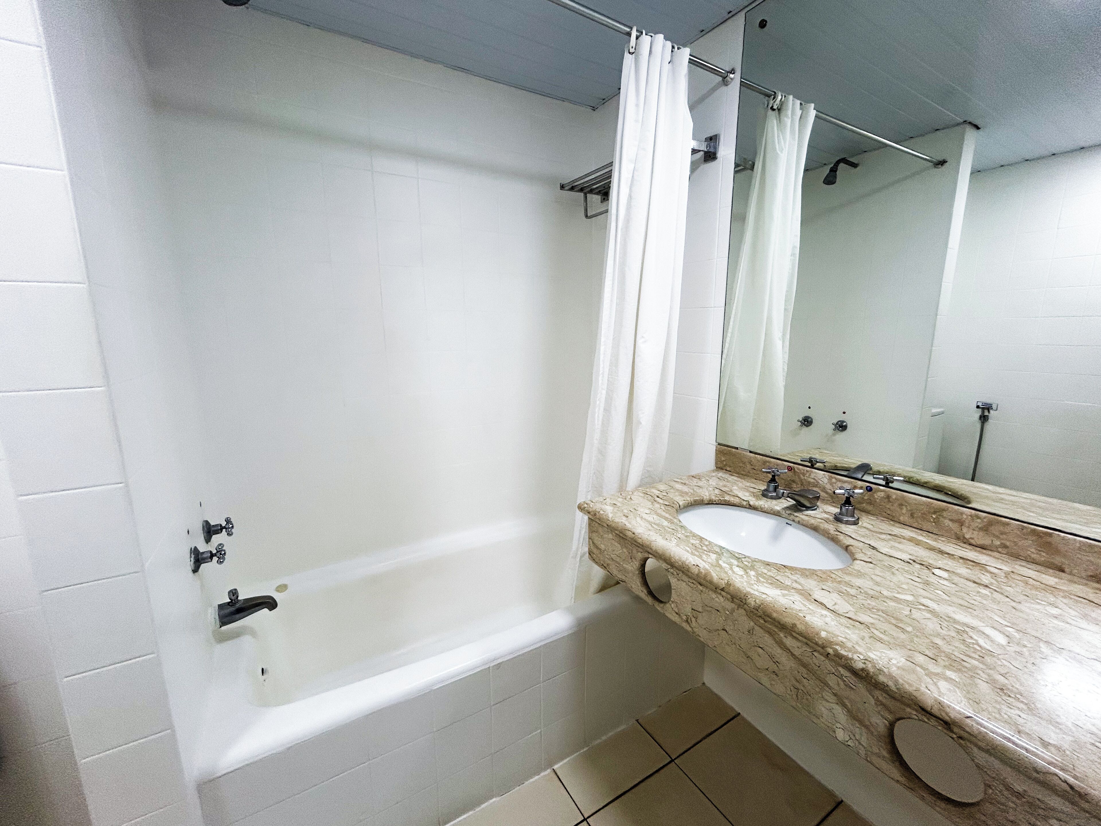A bathroom with a bathtub, two sinks, a mirror, and a shower curtain.