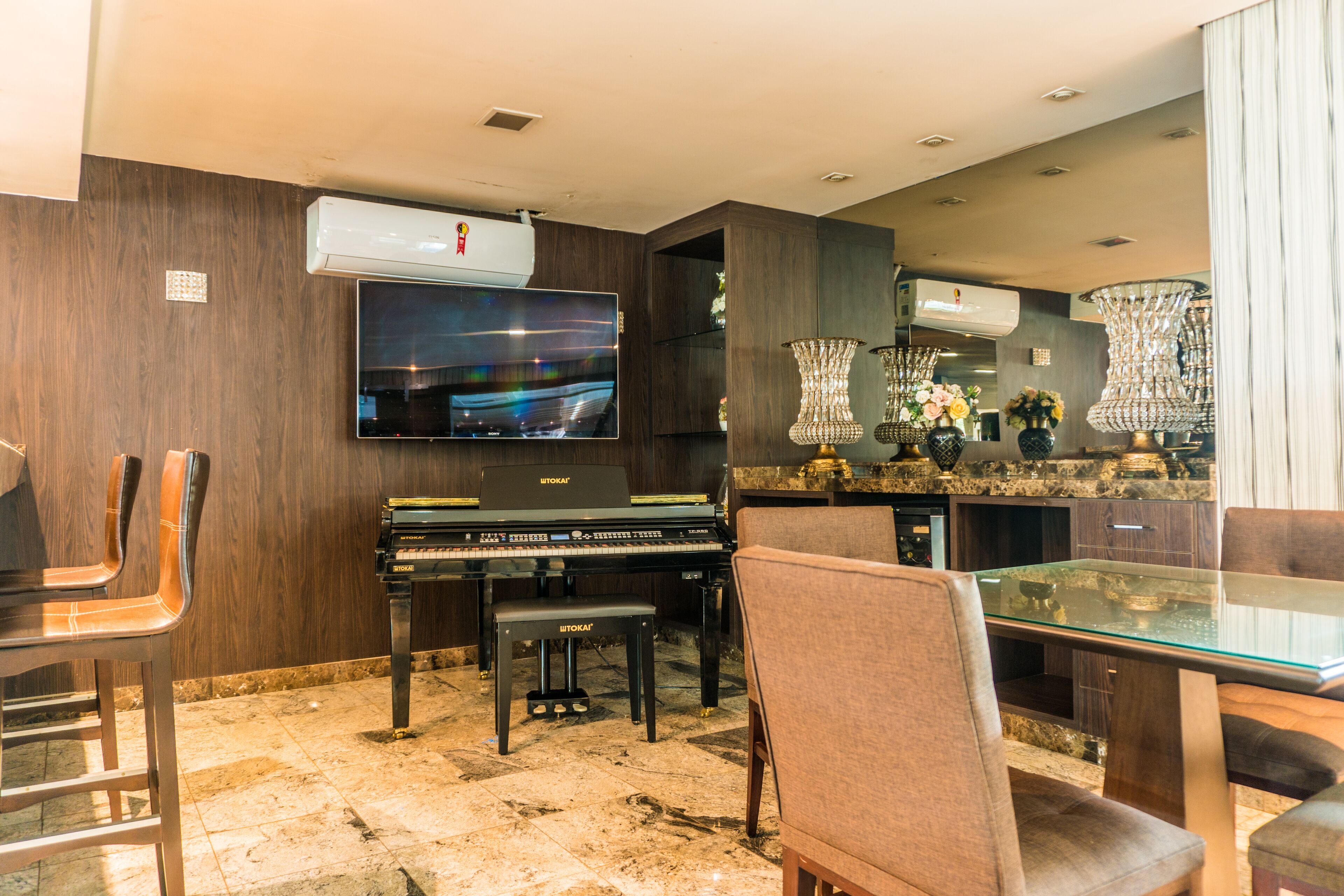 A modern living room with a piano, a flat-screen TV, and a glass-top dining table with chairs.
