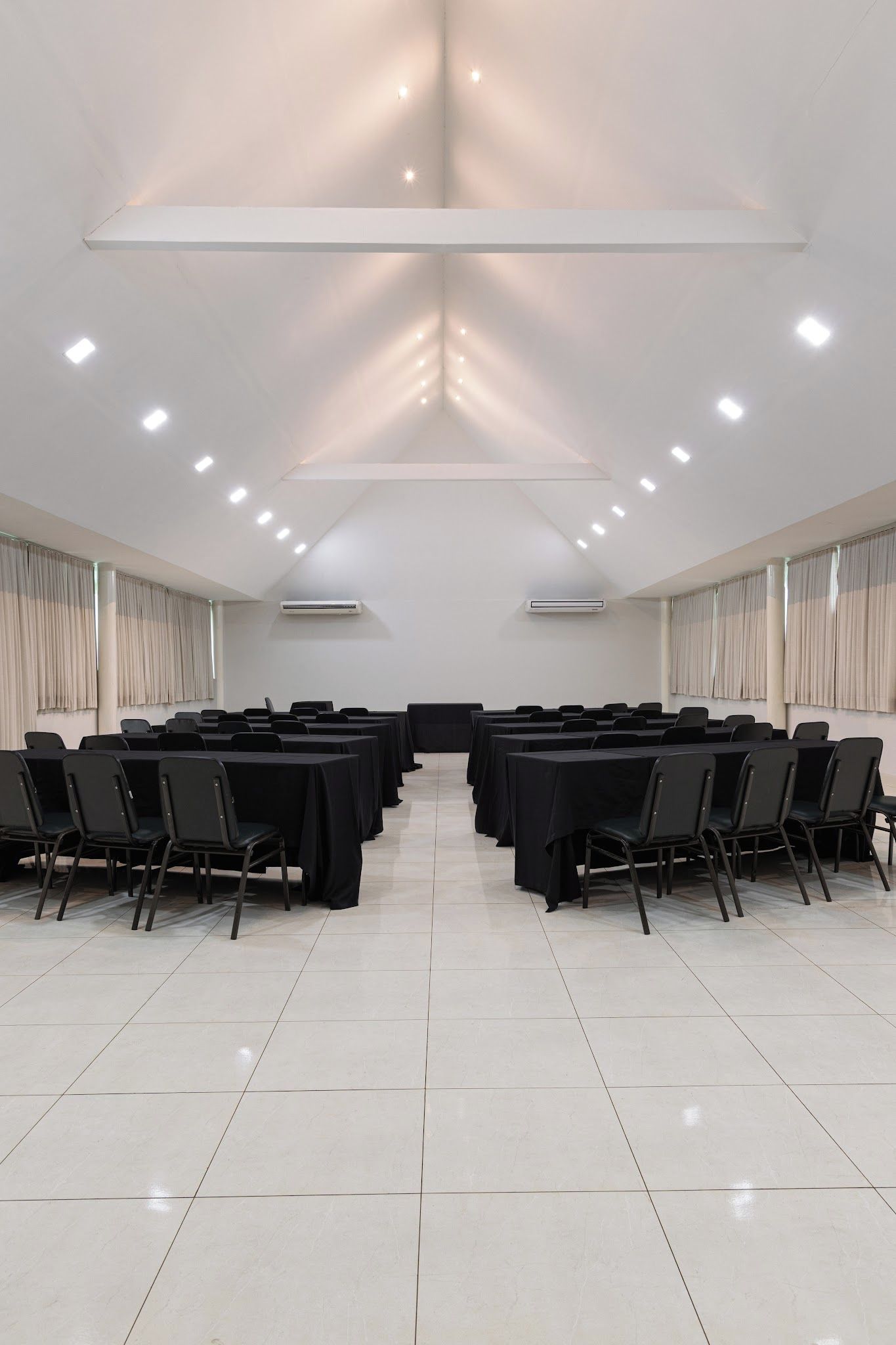Une salle de conférence avec une longue table, des chaises et des luminaires au plafond.