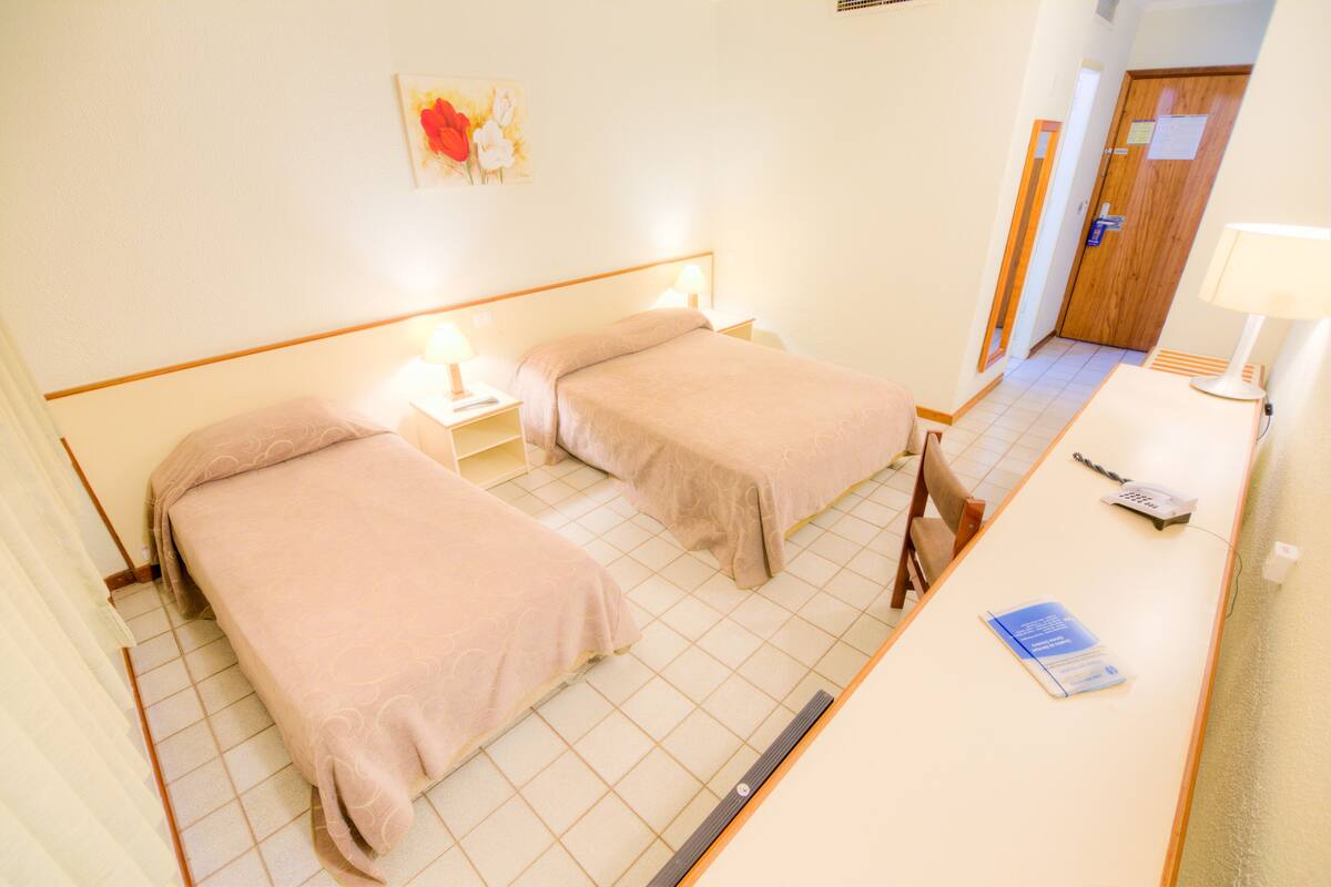 Habitación de hotel con dos camas, un escritorio y una silla.
