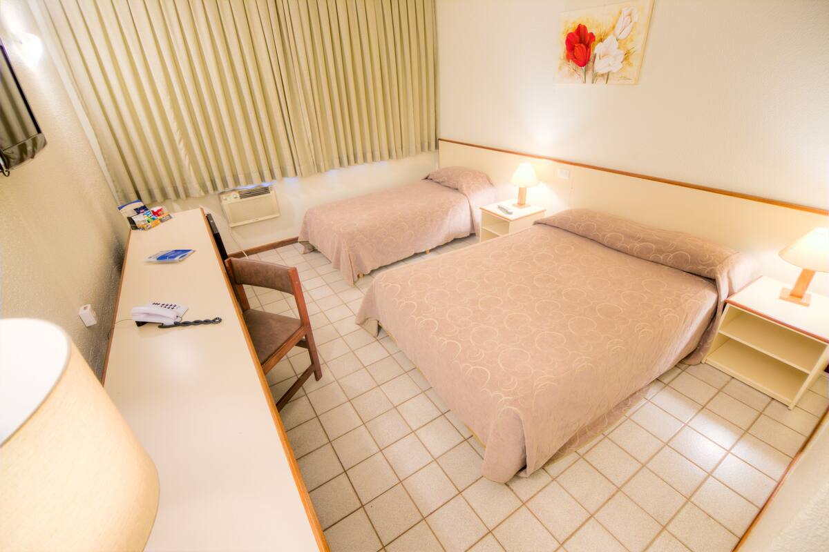 Habitación de hotel con dos camas, un escritorio, una silla, un teléfono y una lámpara.