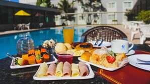 A breakfast buffet at the DAN Inn Hotel with a pool in the background. - Hotel Dan Inn Uberaba & Convenções by Nacional Inn (Uberaba)