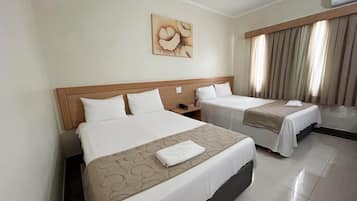 A hotel room with two beds, a headboard, a nightstand, a painting on the wall, and a window with curtains.