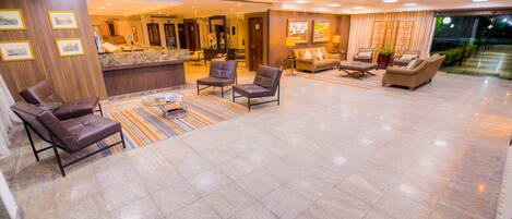 A spacious lobby with a reception desk, multiple seating areas, and a view of the outdoor area.