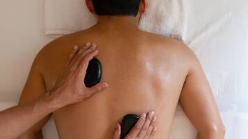 A person receiving a back massage with a stone on their back.