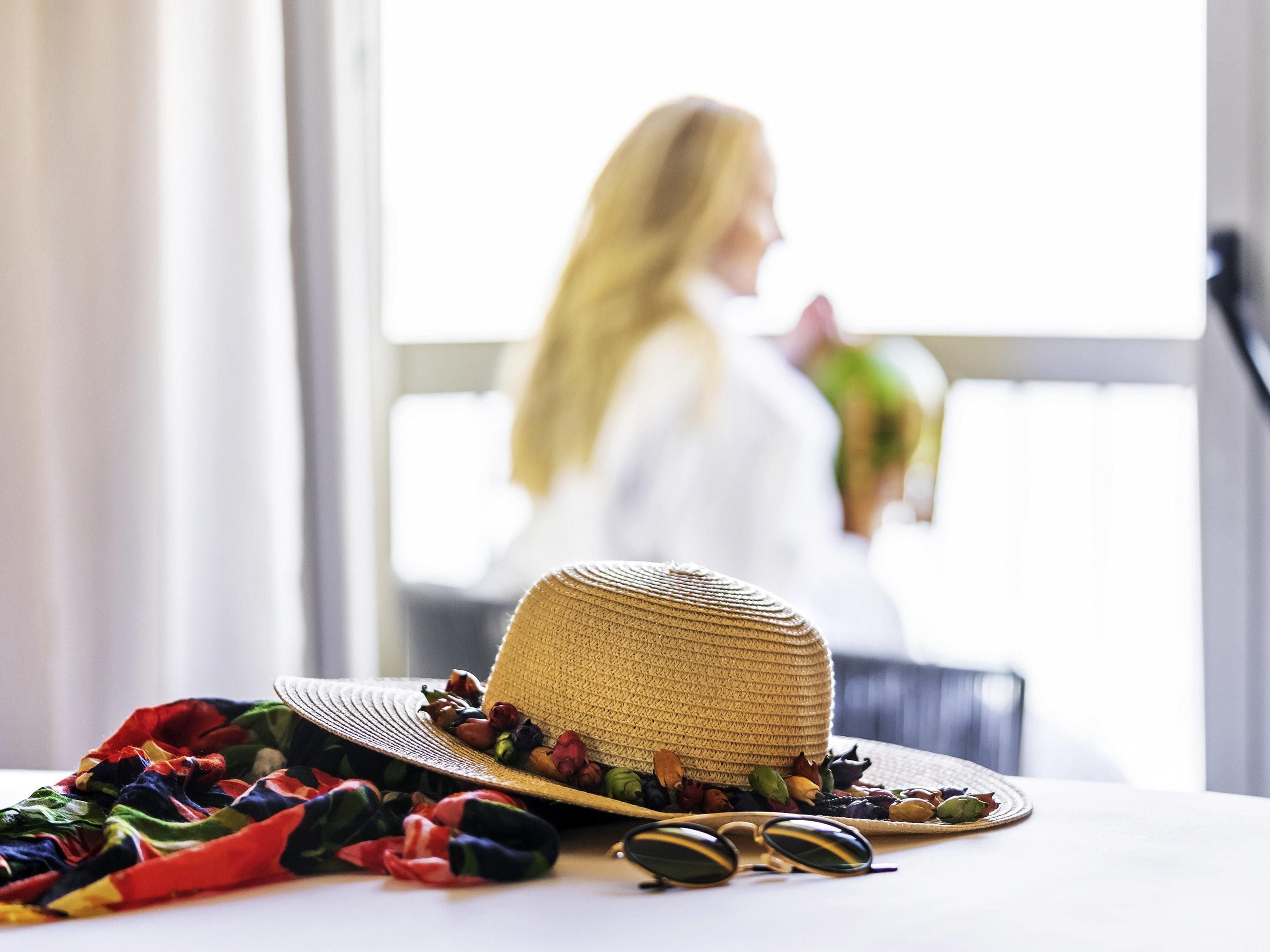 A straw hat with sunglasses and colorful fabric on a table.
