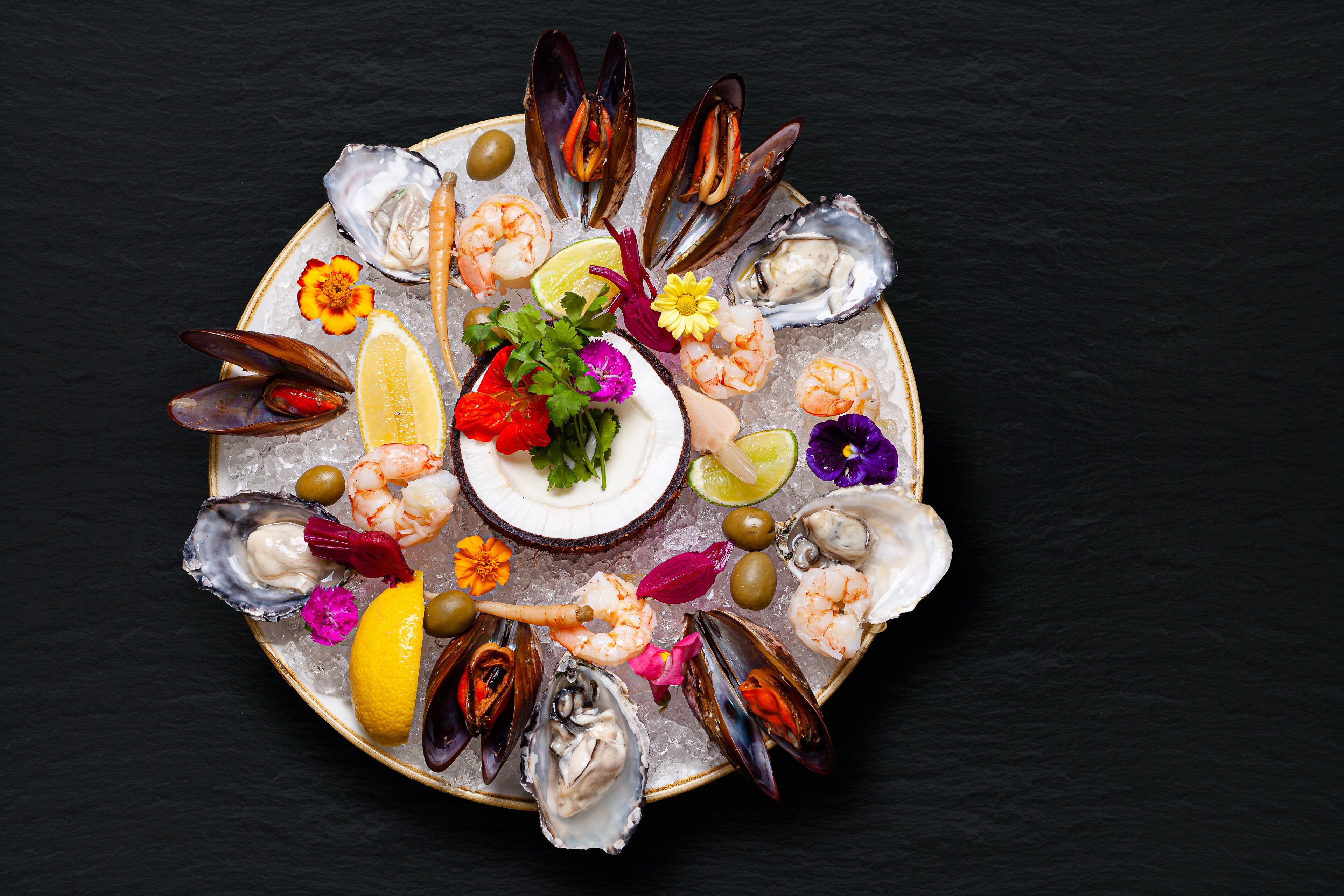 A seafood platter with various types of shellfish, shrimp, and garnishes on a plate.