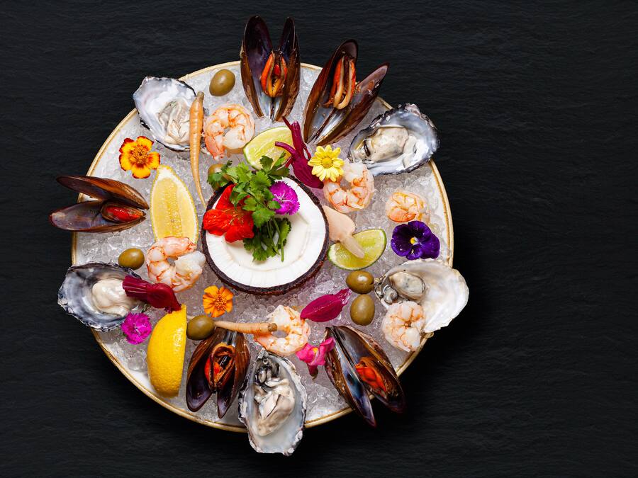 A seafood platter with various types of shellfish, shrimp, and garnishes on a plate.