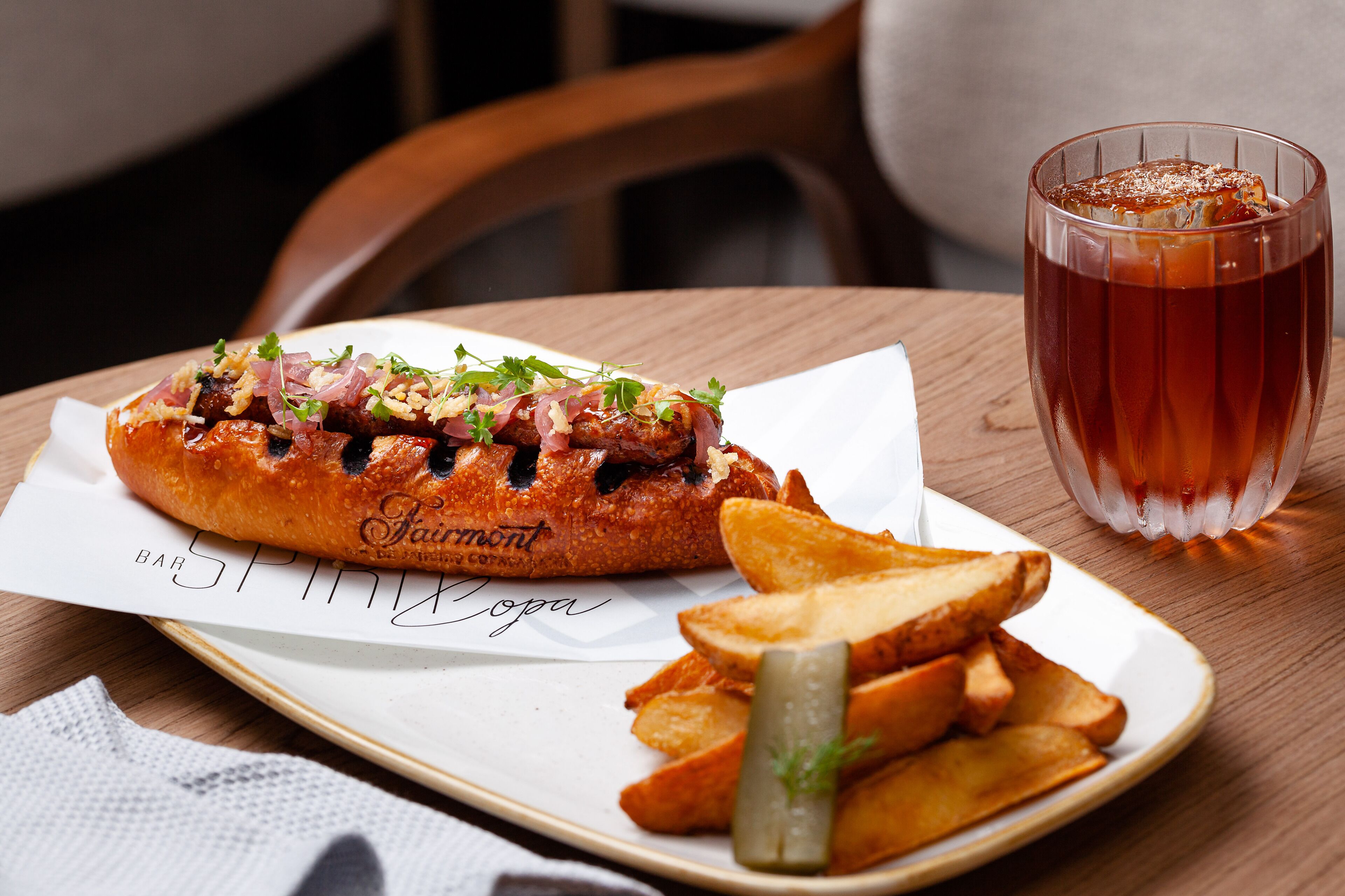 A plate with a grilled sandwich, fries, and a glass of iced tea on a wooden table.