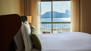 A hotel room with a large bed, a view of the sea, and a balcony with outdoor furniture. - Fairmont Rio de Janeiro Copacabana (Rio de Janeiro)