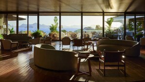 A spacious lounge area with a view of the sea and mountains, featuring modern furniture and large windows. - Fairmont Rio de Janeiro Copacabana (Rio de Janeiro)