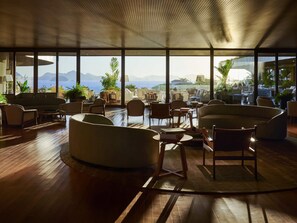 Un vaste salon avec vue sur la mer et les montagnes, dotĂ© de meubles modernes et de grandes fenĂȘtres.