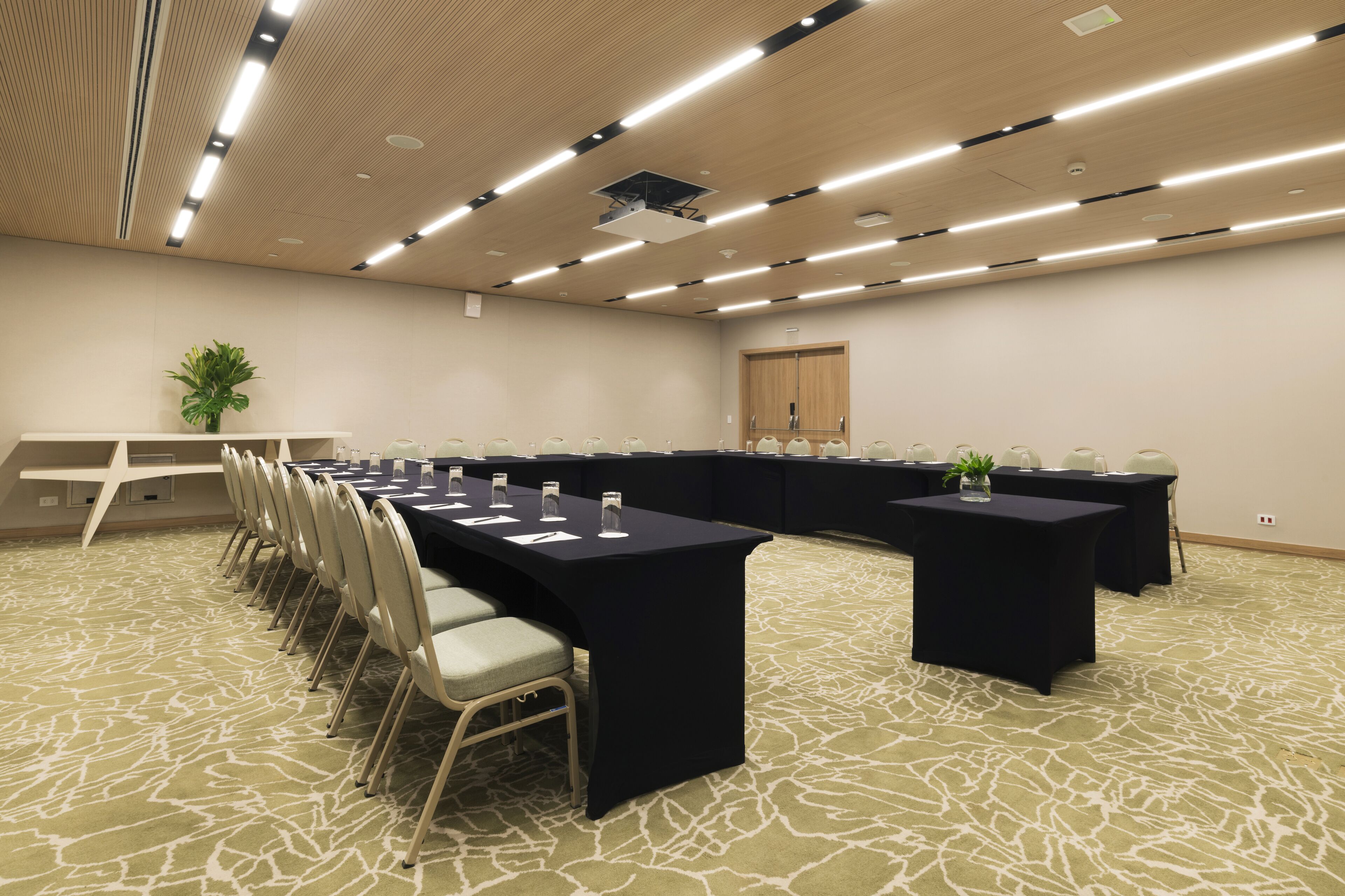 Ett konferensrum med långa bord, stolar och en projektor i taket.