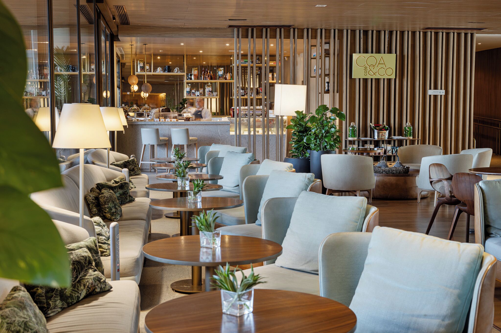 A modern hotel lobby with seating areas, a bar, and a reception desk.