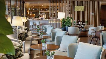 A modern hotel lobby with seating areas, a bar, and a reception desk.
